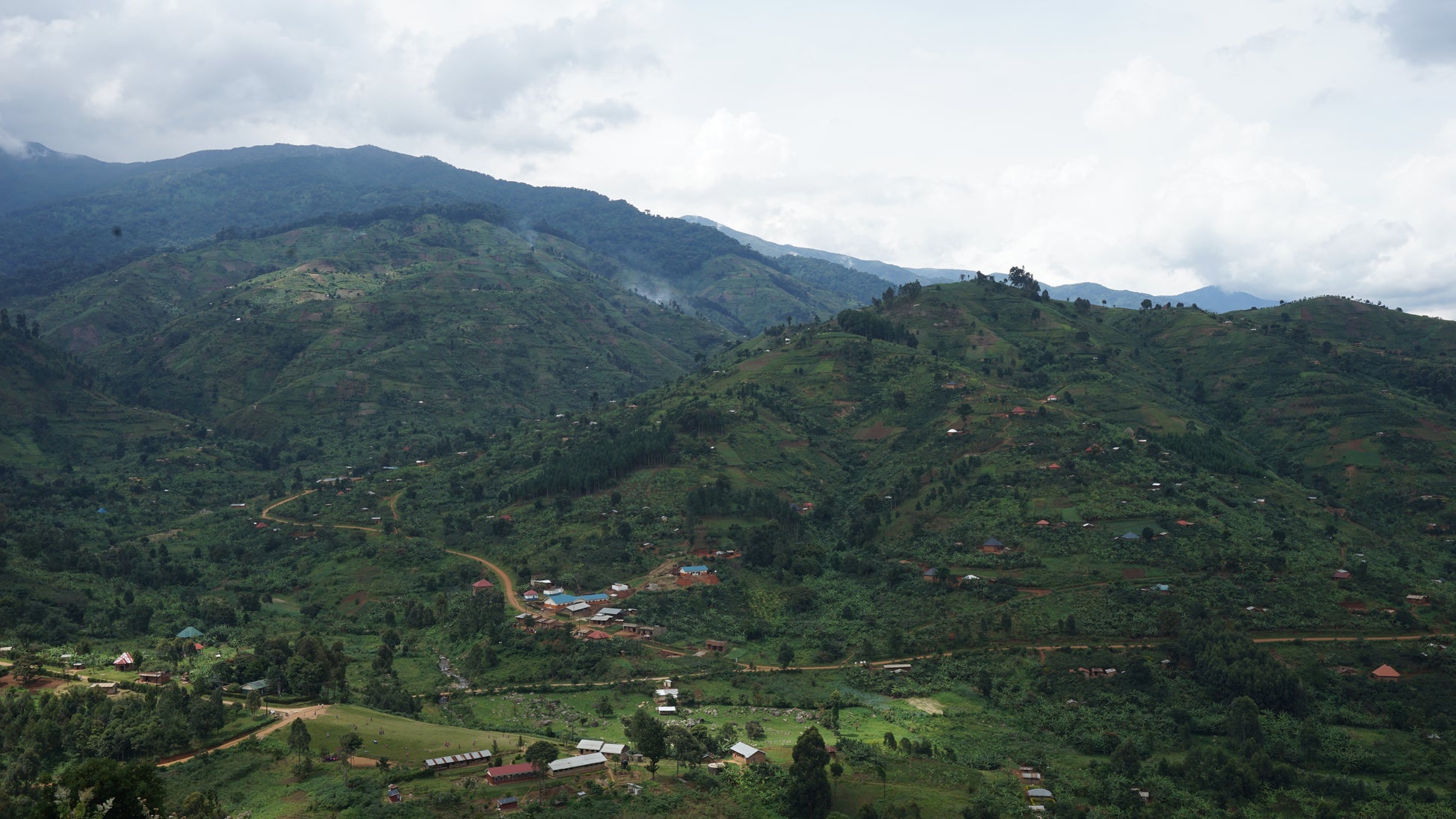 Hilly landscape with scattered buildings under a cloudy sky