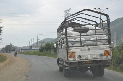 Truck carrying bags on a road with power lines and hills in the background