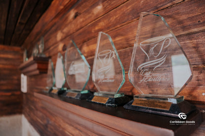 Row of glass awards on a wooden shelf with 'Caribbean Goods' branding.