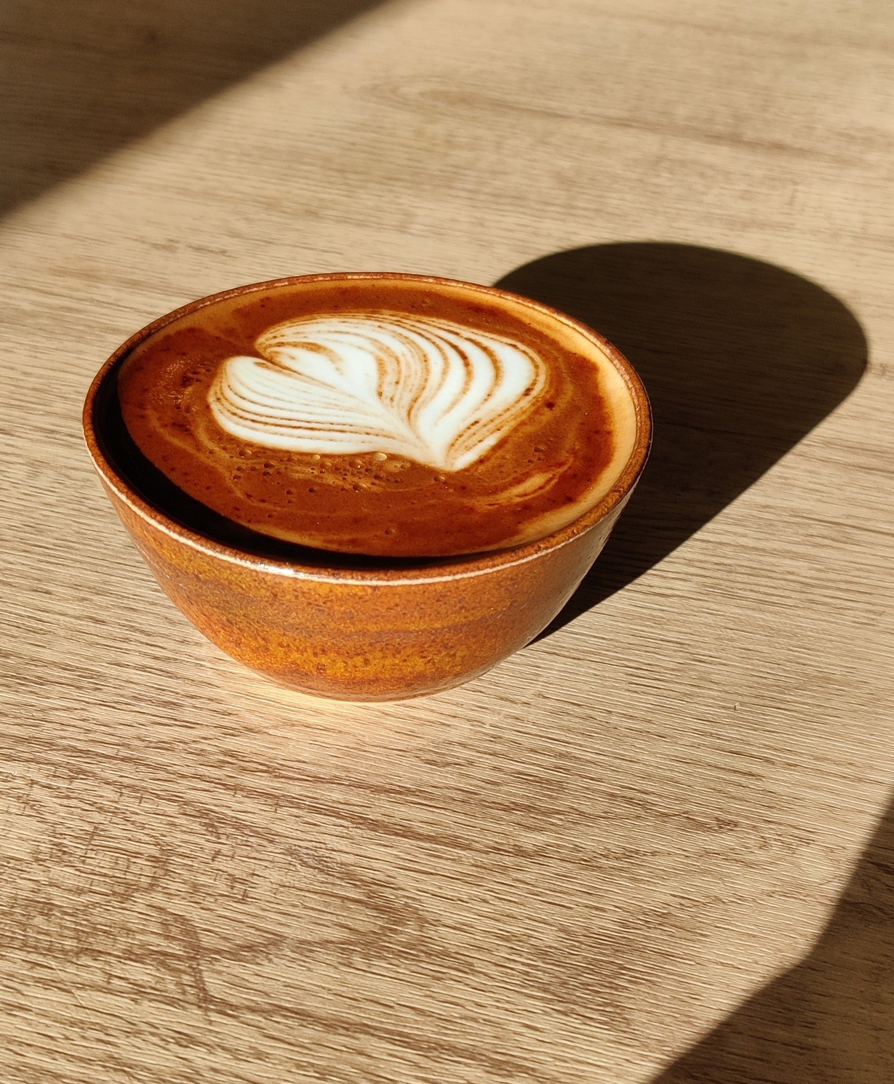 Ceramic cup with a latte art design on a wooden surface