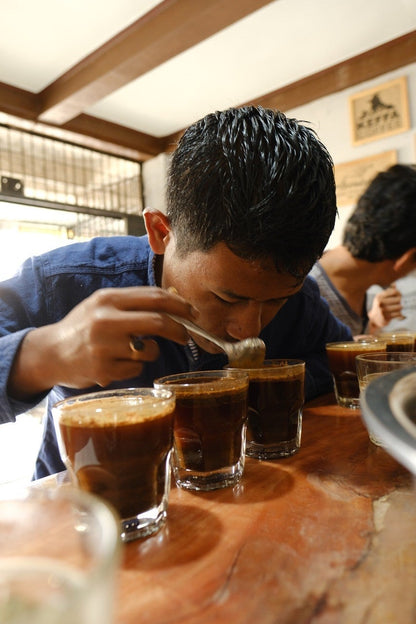 Person tasting coffee in a bar setting