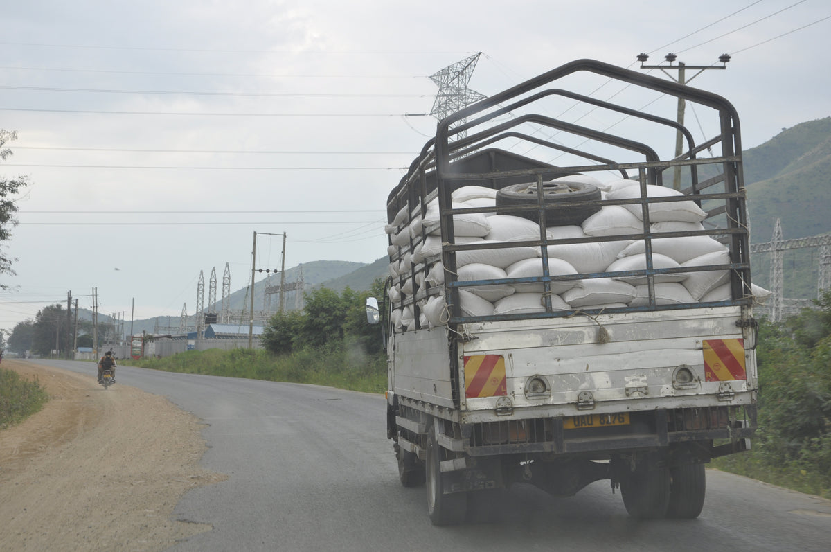 Truck carrying bags on a road with power lines and hills in the background